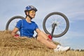 Beautiful girl cyclist sitting on dry grass on the background of the bike Royalty Free Stock Photo