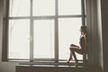 Beautiful girl dancer with long flowing hair in black clothes, swimsuit,in a beautiful beautiful pose on the big window Daylight, Royalty Free Stock Photo