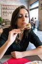 Beautiful girl with dark hair, dressed in black is holding chopsticks with sushi Royalty Free Stock Photo