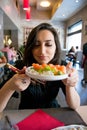 Beautiful girl with dark hair, dressed in black is holding a plate full of sashimi sushi Royalty Free Stock Photo