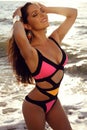 Beautiful girl with dark hair in elegant bright bikini posing on beach Royalty Free Stock Photo