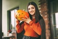 A beautiful girl with dark hair with makeup for the celebration of Halloween holds a pumpkin in her hands and smiles.