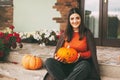 A beautiful girl with dark hair with makeup for the celebration of Halloween holds a pumpkin in her hands and smiles.