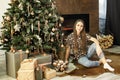 a beautiful girl decorates a Christmas tree in a large living room with a fireplace. beautiful interior. concept of waiting for Royalty Free Stock Photo