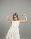 A little girl shows her strength. A beautiful young girl demonstrating the strength of her arms poses in a light light