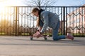 beautiful girl in denim clothes and pink sneakers does exercises on a penny board, a longboard. International Skateboarding Day.