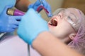Beautiful girl in dental chair on the examination at dentist. Woman showing her perfect straight white teeth. Technology