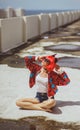 Beautiful girl devil sitting on city background near the puddle with his reflection. In anticipation of Halloween Royalty Free Stock Photo