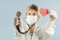 Beautiful girl doctor with a red heart in her hands on a blue isolated background.Concept of love