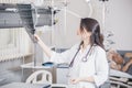 Beautiful girl doctor in a white coat examines X-ray photo of the patient to identify the problem. Professional conversation, cons