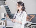 Beautiful girl doctor in a white coat examines X-ray photo of the patient to identify the problem. Professional conversation, cons