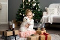 Beautiful girl with dog sitting near the Christmas tree. Merry Christmas and Happy Holidays. Royalty Free Stock Photo