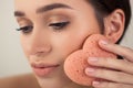 Beautiful girl doing makeup with a heart-shaped sponge. Royalty Free Stock Photo