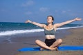 A beautiful girl is doing yoga on the beach near the sea Royalty Free Stock Photo