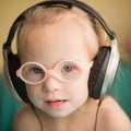 Beautiful girl with Down syndrome is listening to music on headphones Royalty Free Stock Photo