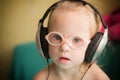 Beautiful girl with Down syndrome is listening to music on headphones Royalty Free Stock Photo