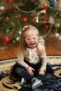 Beautiful girl with Down syndrome sits near a Christmas tree
