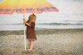 Beautiful girl with Down syndrome standing under an umbrella on the beach Royalty Free Stock Photo