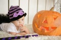 Beautiful girl with Down syndrome thoughtfully keeps finger in the mouth near the big pumpkin Royalty Free Stock Photo