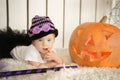 Beautiful girl with Down syndrome thoughtfully keeps finger in the mouth near the big pumpkin Royalty Free Stock Photo