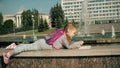 Beautiful girl draws in a notebook near the fountain