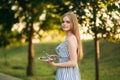 Beautiful girl draws a picture in the park using a palette with paints and a spatula. Easel and canvas with a picture. Summer is a Royalty Free Stock Photo