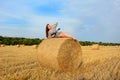 A beautiful girl dreamily lies on a bale of straw with a ukulele in her hands