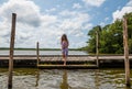 beautiful girl in dress and bare feet on a wooden pontoon by the lake