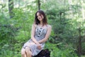 Beautiful girl in dress sitting on stump in forest