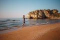 Beautiful girl in a dress walks along the sea sandy shore at sunset Royalty Free Stock Photo