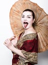 Beautiful girl dressed as a geisha girl holding a Chinese umbrella. Geisha makeup and hair dressed in a kimono. The