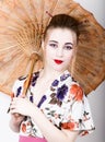 Beautiful girl dressed as a geisha girl holding a Chinese umbrella. Geisha makeup and hair dressed in a kimono. The