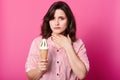 Beautiful girl dressed red and white striped shirt, holds huge ice cream in waffle cone with kiwi taste. Brunette woman keeps hand Royalty Free Stock Photo