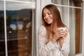 Beautiful girl drinking coffee on the balcony. Portrait of a happy woman thinking and looking away Royalty Free Stock Photo