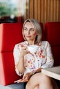 A beautiful girl is drinking coffee in a cafe and looking thoughtfully into the distance Royalty Free Stock Photo