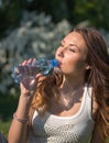 Beautiful girl is drinking water from a bottle in the park Royalty Free Stock Photo