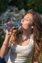 Beautiful girl is drinking water from a bottle in the park Royalty Free Stock Photo