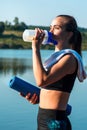 Beautiful girl drinks water during a sports training on a background of beautiful nature Royalty Free Stock Photo