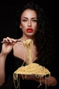 A beautiful girl eats with a fork spaghetti with red lips.