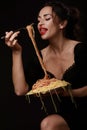 A beautiful girl eats with a fork spaghetti with red lips.