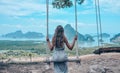 beautiful girl in elegant grey dress sitting on swing with fantastic panoramic view on beautiful Thai bay