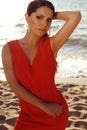 Beautiful girl in elegant red dress relaxing on summer beach Royalty Free Stock Photo