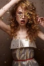 Beautiful girl in an evening dress and gold curls. Model in New Year`s image with glitter and tinsel. Royalty Free Stock Photo