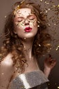 Beautiful girl in an evening dress and gold curls. Model in New Year`s image with glitter and tinsel. Royalty Free Stock Photo