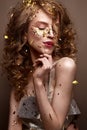 Beautiful girl in an evening dress and gold curls. Model in New Year`s image with glitter and tinsel. Royalty Free Stock Photo