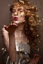 Beautiful girl in an evening dress and gold curls. Model in New Year`s image with glitter and tinsel. Royalty Free Stock Photo