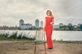 Beautiful girl in evening red dress on the lake with a glass and a bottle of wine. Royalty Free Stock Photo