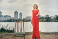 Beautiful girl in evening red dress on the lake with a glass and a bottle of wine. Royalty Free Stock Photo