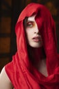Beautiful girl with fashionable makeup in red tones, wearing a red silk scarf thrown over her head that covers her naked breast, Royalty Free Stock Photo