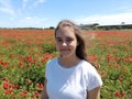 Beautiful girl in a field of blooming red flowers. Wonderful landscape, horizon and blue sky in the background Royalty Free Stock Photo